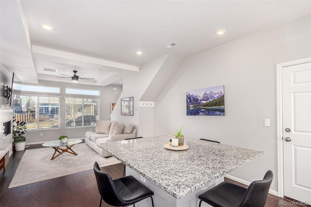 dining area with a raised ceiling, ceiling fan, and dark hardwood / wood-style floors