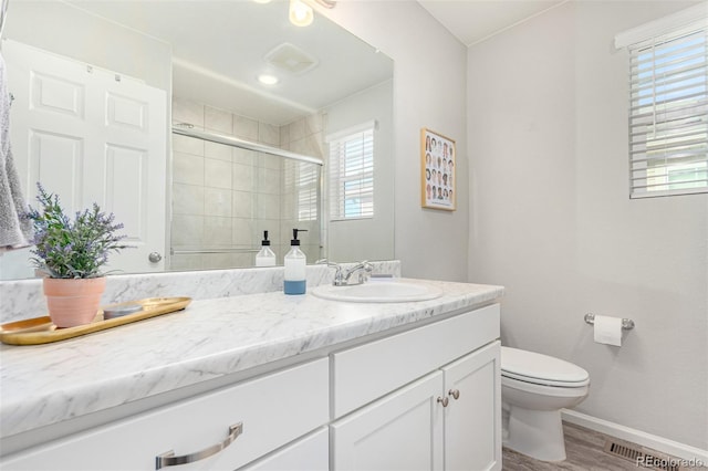 bathroom featuring hardwood / wood-style floors, vanity, toilet, and a shower with door