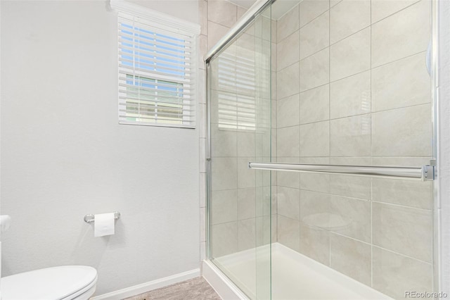 bathroom with a shower with shower door and toilet