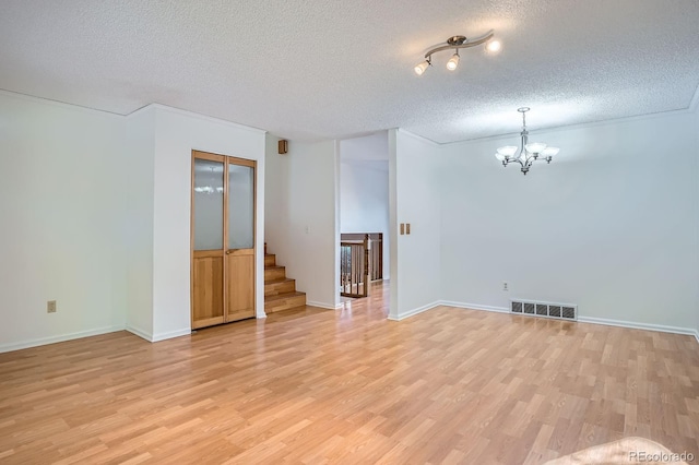 4664 S Zang St, Morrison, CO 80465 - unfurnished room featuring a textured ceiling, a chandelier, light wood-type flooring, and stairs