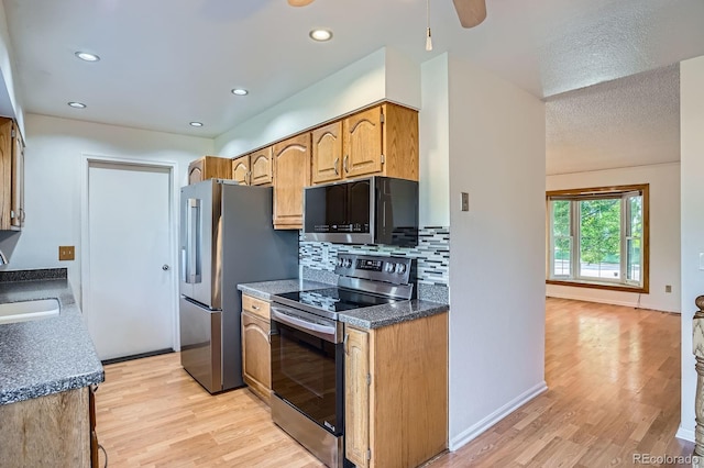 4664 S Zang St, Morrison, CO 80465 - kitchen featuring stainless steel appliances, light wood-style floors, tasteful backsplash, dark countertops, and recessed lighting