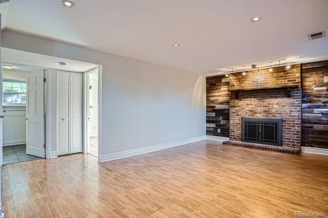 4664 S Zang St, Morrison, CO 80465 - unfurnished living room with rail lighting, wood finished floors, a fireplace, recessed lighting, and wood walls