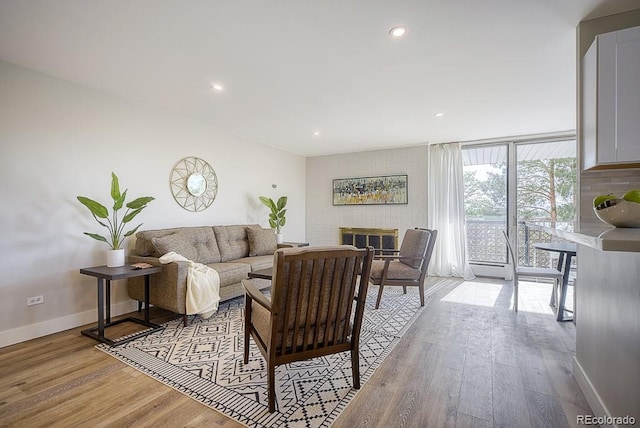 living room featuring floor to ceiling windows, light hardwood / wood-style floors, and a brick fireplace