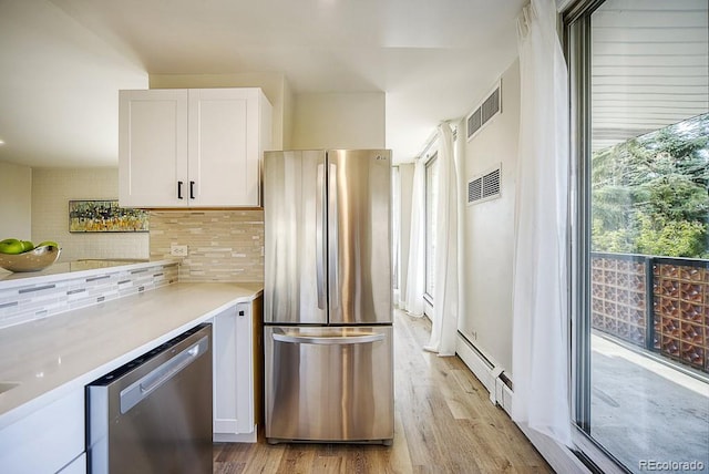 kitchen with tasteful backsplash, white cabinets, light hardwood / wood-style floors, and appliances with stainless steel finishes