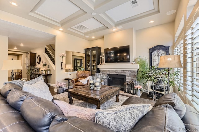 living room featuring beam ceiling, a stone fireplace, and coffered ceiling