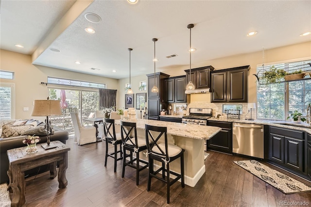 kitchen with a center island, a kitchen bar, decorative backsplash, sink, and stainless steel appliances