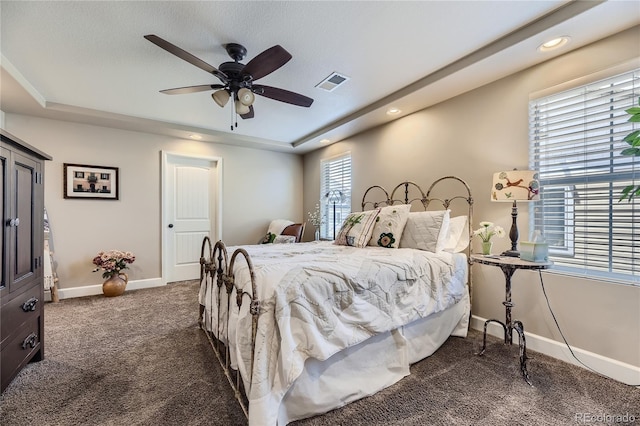 bedroom with ceiling fan, a raised ceiling, and dark colored carpet