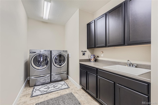 clothes washing area featuring sink, separate washer and dryer, a textured ceiling, and cabinets