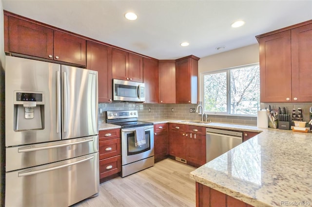 9889 Aftonwood St, Highlands Ranch, CO 80126 - kitchen with appliances with stainless steel finishes, a sink, light stone countertops, tasteful backsplash, and light wood-style floors