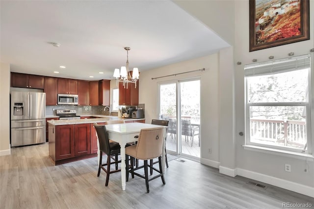 9889 Aftonwood St, Highlands Ranch, CO 80126 - kitchen featuring appliances with stainless steel finishes, a chandelier, light countertops, light wood-style flooring, and a kitchen island