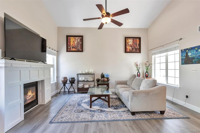 9889 Aftonwood St, Highlands Ranch, CO 80126 - living area featuring wood finished floors, a ceiling fan, a glass covered fireplace, baseboards, and lofted ceiling