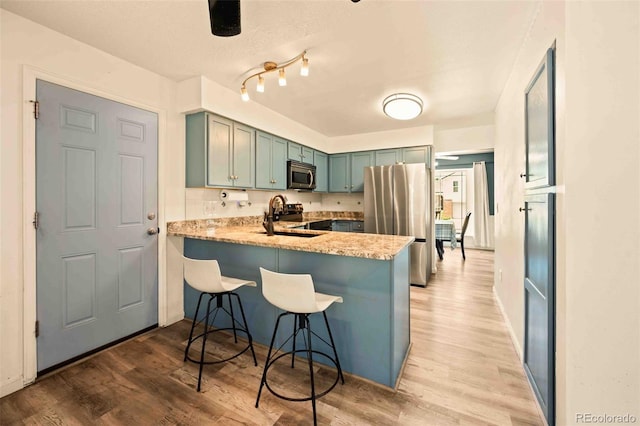 12234 W Saratoga Ave, Morrison, CO 80465 - kitchen with appliances with stainless steel finishes, light wood-type flooring, a peninsula, and a kitchen bar