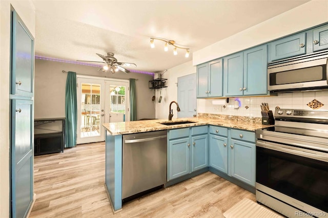 12234 W Saratoga Ave, Morrison, CO 80465 - kitchen featuring appliances with stainless steel finishes, a peninsula, light wood-style floors, ceiling fan, and decorative backsplash