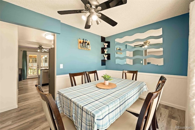 12234 W Saratoga Ave, Morrison, CO 80465 - dining area featuring ceiling fan, wood finished floors, wainscoting, and a textured ceiling
