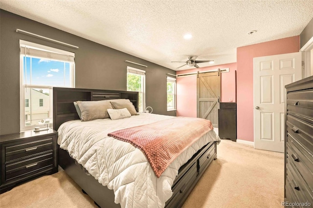 12234 W Saratoga Ave, Morrison, CO 80465 - bedroom with a barn door, light colored carpet, a textured ceiling, and ceiling fan