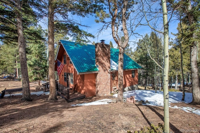 exterior space featuring a chimney and metal roof