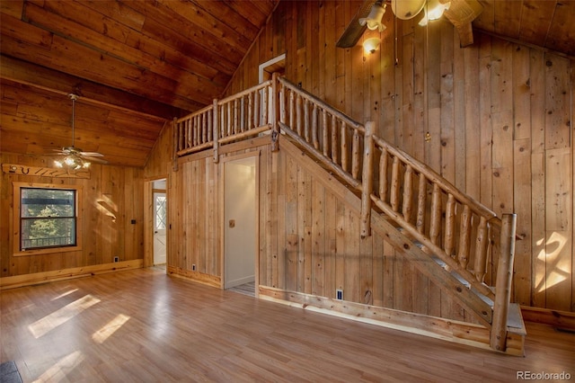 unfurnished living room featuring wooden ceiling, wooden walls, wood finished floors, and a ceiling fan