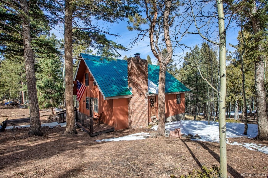 exterior space with a wooden deck, a chimney, and metal roof