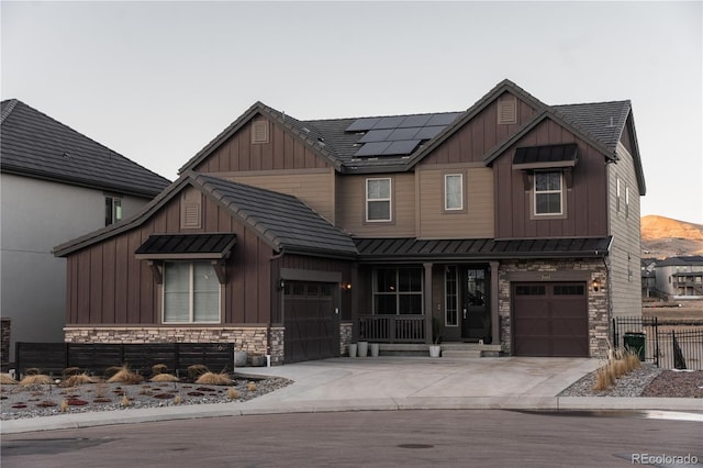 view of front facade with a garage, a mountain view, covered porch, and solar panels