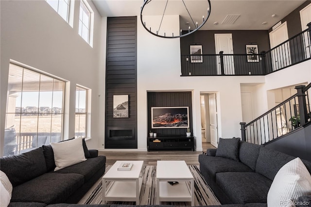 living room with an inviting chandelier, wood-type flooring, and a large fireplace