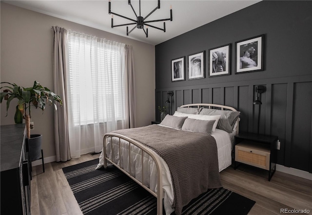 bedroom with wood-type flooring and an inviting chandelier