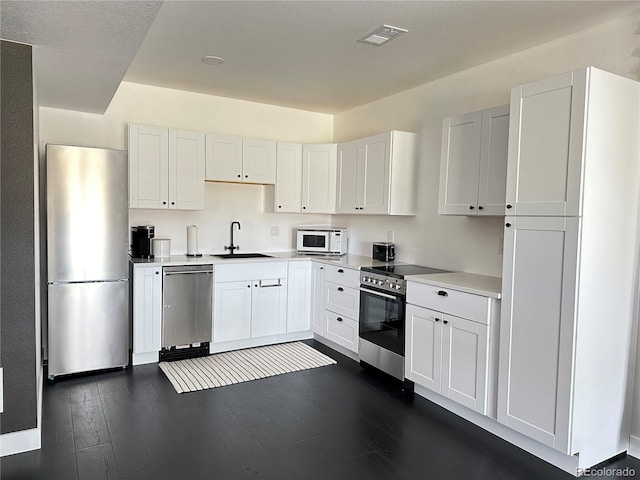 kitchen with white cabinetry, appliances with stainless steel finishes, dark hardwood / wood-style floors, and sink