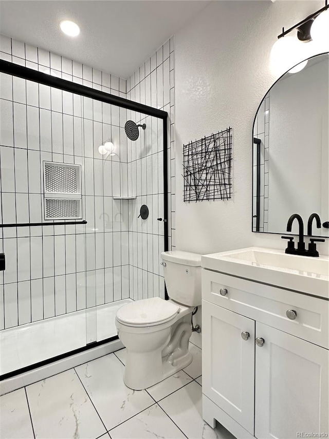 bathroom with vanity, toilet, and a shower with door