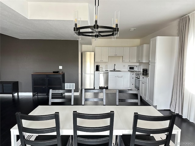 kitchen featuring sink, appliances with stainless steel finishes, white cabinetry, a kitchen island, and a chandelier