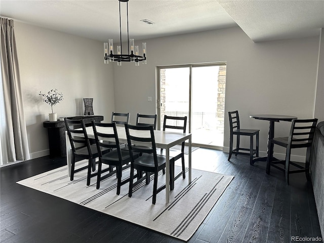 dining area with dark hardwood / wood-style flooring, a notable chandelier, and a textured ceiling