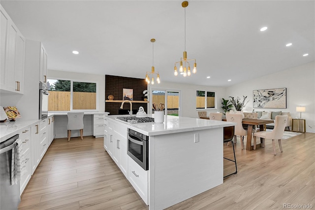 8357 Dudley Ct, Arvada, CO 80005 - kitchen with stainless steel appliances, light wood-style flooring, recessed lighting, white cabinetry, and a chandelier