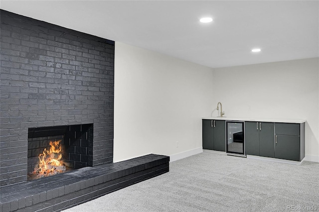 8357 Dudley Ct, Arvada, CO 80005 - unfurnished living room featuring wine cooler, a brick fireplace, light colored carpet, recessed lighting, and wet bar