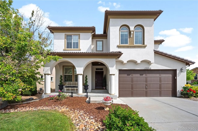 15205 W Baker Ave, Lakewood, CO 80228 - mediterranean / spanish-style home with a porch, stucco siding, concrete driveway, an attached garage, and a tile roof