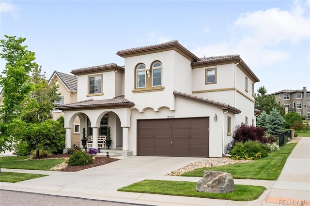 15205 W Baker Ave, Lakewood, CO 80228 - mediterranean / spanish-style house featuring a garage, covered porch, concrete driveway, a tiled roof, and stucco siding
