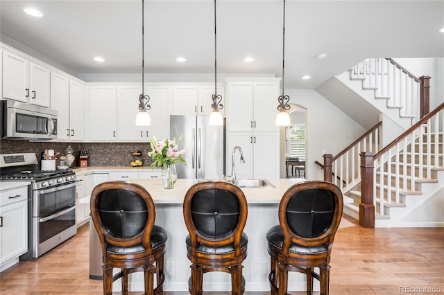 15205 W Baker Ave, Lakewood, CO 80228 - kitchen with appliances with stainless steel finishes, a sink, light wood-style flooring, light countertops, and white cabinetry