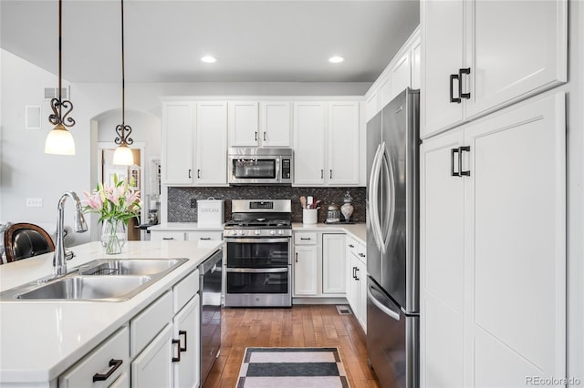 15205 W Baker Ave, Lakewood, CO 80228 - kitchen featuring stainless steel appliances, a sink, dark wood finished floors, white cabinetry, and light countertops