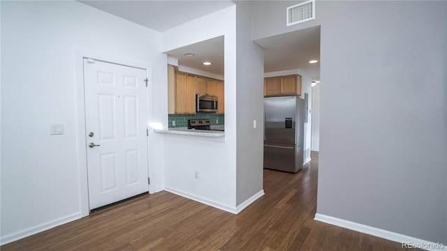 kitchen featuring stainless steel appliances, dark hardwood / wood-style floors, and backsplash