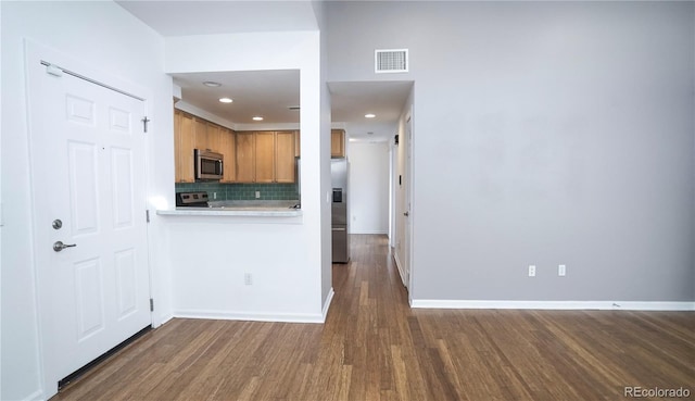 kitchen with tasteful backsplash, stainless steel appliances, and dark hardwood / wood-style flooring