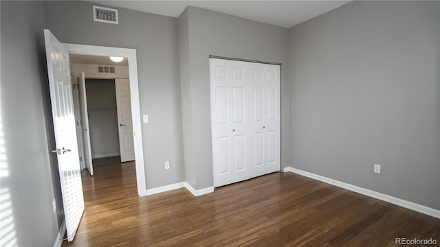 unfurnished bedroom with dark hardwood / wood-style flooring and a closet