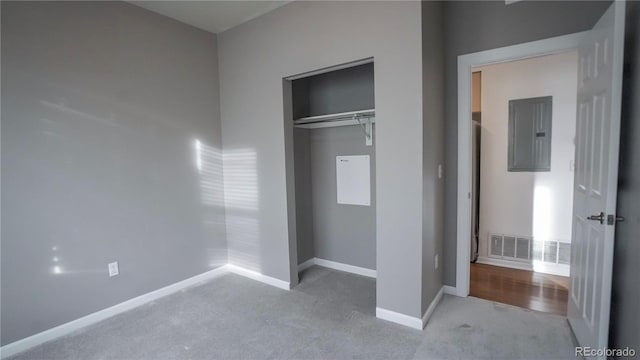 unfurnished bedroom with light carpet, electric panel, and a closet