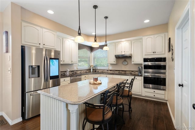 kitchen featuring a kitchen island, appliances with stainless steel finishes, sink, white cabinets, and hanging light fixtures