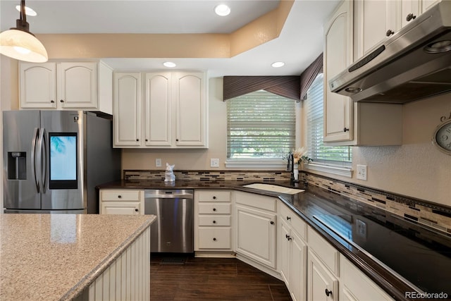 kitchen with sink, dark stone countertops, hanging light fixtures, stainless steel appliances, and white cabinets