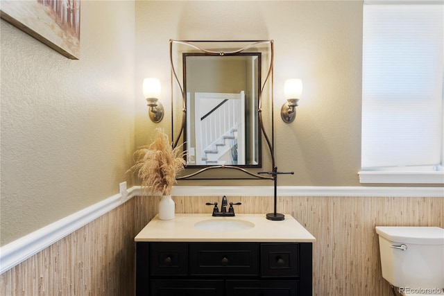 bathroom with vanity, wooden walls, and toilet