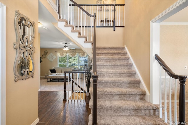 staircase with wood-type flooring and a high ceiling