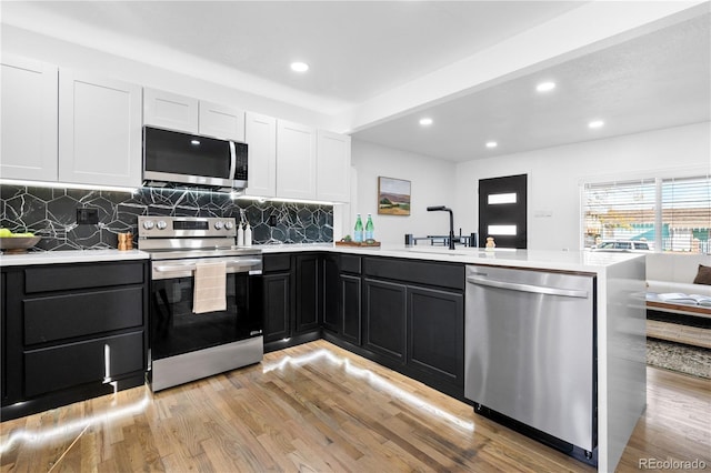 kitchen featuring sink, white cabinets, light wood-type flooring, and appliances with stainless steel finishes