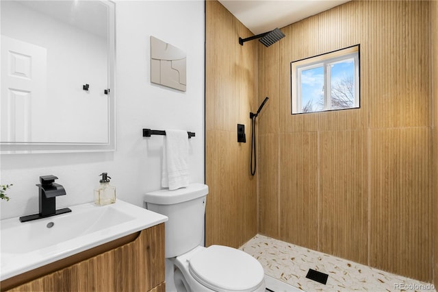 bathroom with a tile shower, vanity, and toilet