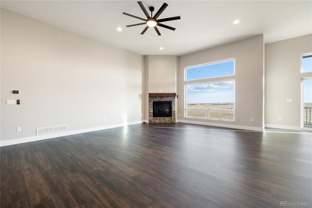 unfurnished living room featuring ceiling fan, dark wood-type flooring, and a fireplace