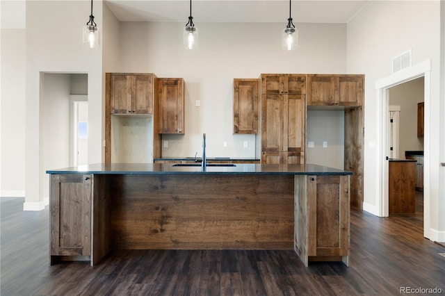 kitchen with decorative light fixtures, a center island with sink, and sink