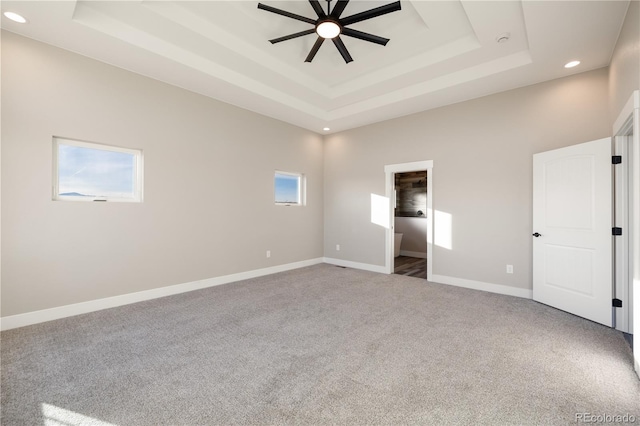 unfurnished bedroom with carpet floors and a tray ceiling