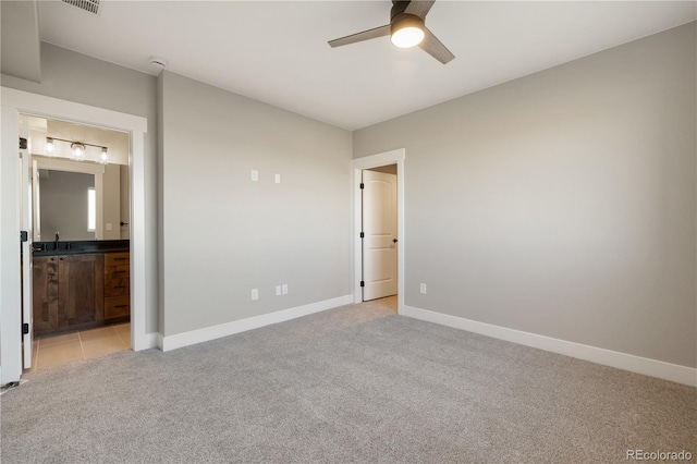 unfurnished bedroom featuring sink, ensuite bathroom, ceiling fan, and light colored carpet