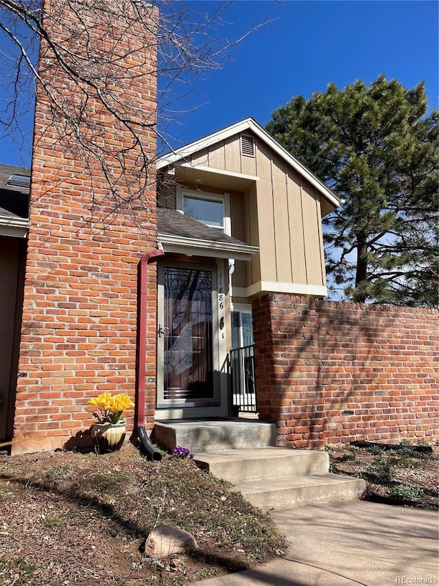 view of exterior entry featuring board and batten siding and brick siding